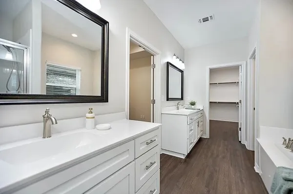 a bathroom with a double vanity sink mirror and bathtub