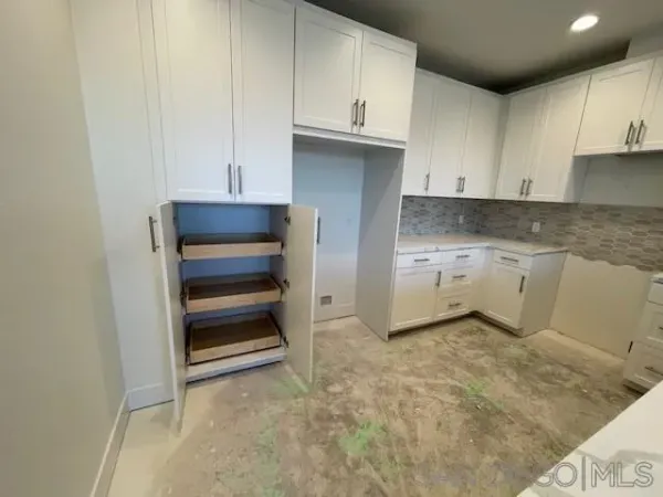 a kitchen with granite countertop a refrigerator and cabinets