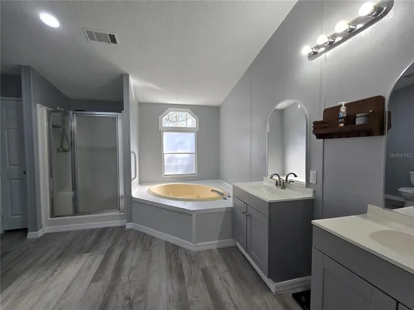 a spacious bathroom with a tub sink and mirror