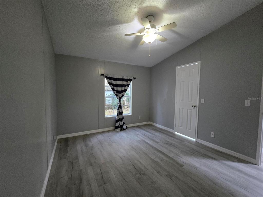 55921 Fern Road Astor, FL 32102 - Photo 16 of 24 an empty room with wooden floor and windows