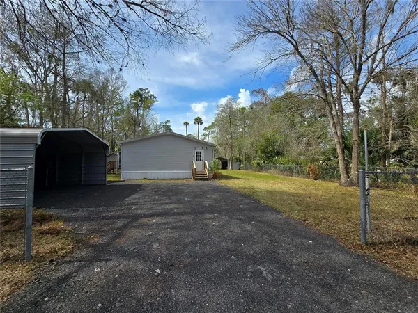 a view of a house with backyard and trees