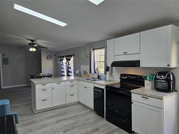 a kitchen with a sink dishwasher a stove and white cabinets