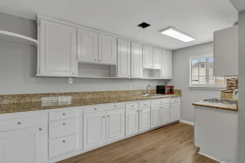 a kitchen with granite countertop white cabinets and white stainless steel appliances