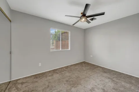an empty room with a ceiling fan and window