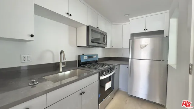 a kitchen with stainless steel appliances granite countertop a refrigerator a stove and a sink