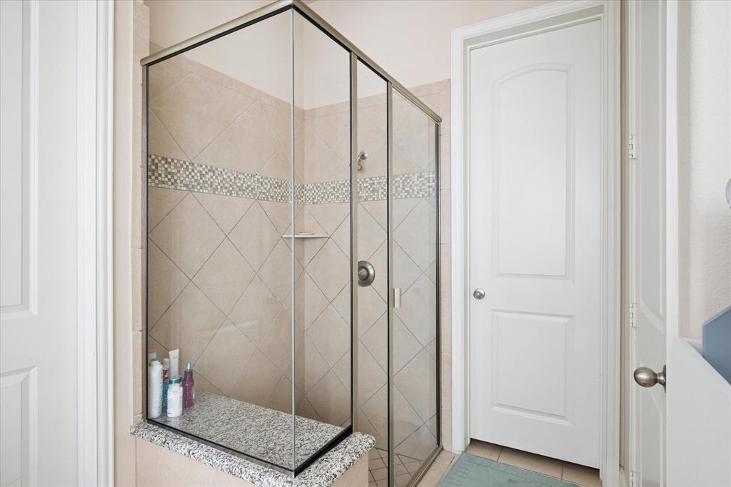 8268 Kara Creek Road Frisco, TX 75036 - Photo 14 of 31 Glass-enclosed shower featuring large format diagonal tile with a mosaic accent band and a built-in granite bench
