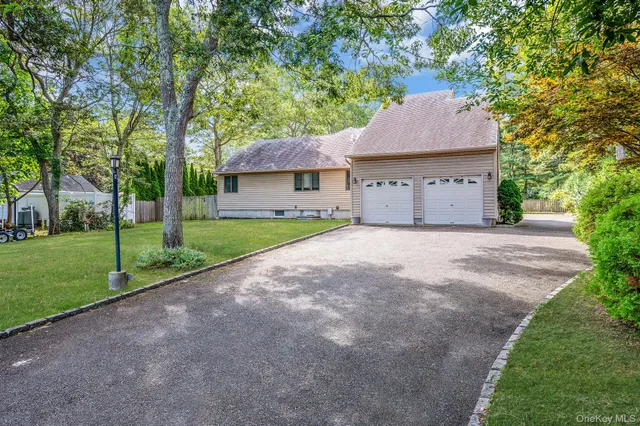 a view of a house with a yard and large trees