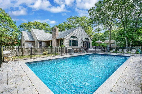 a view of swimming pool with sitting area and large trees