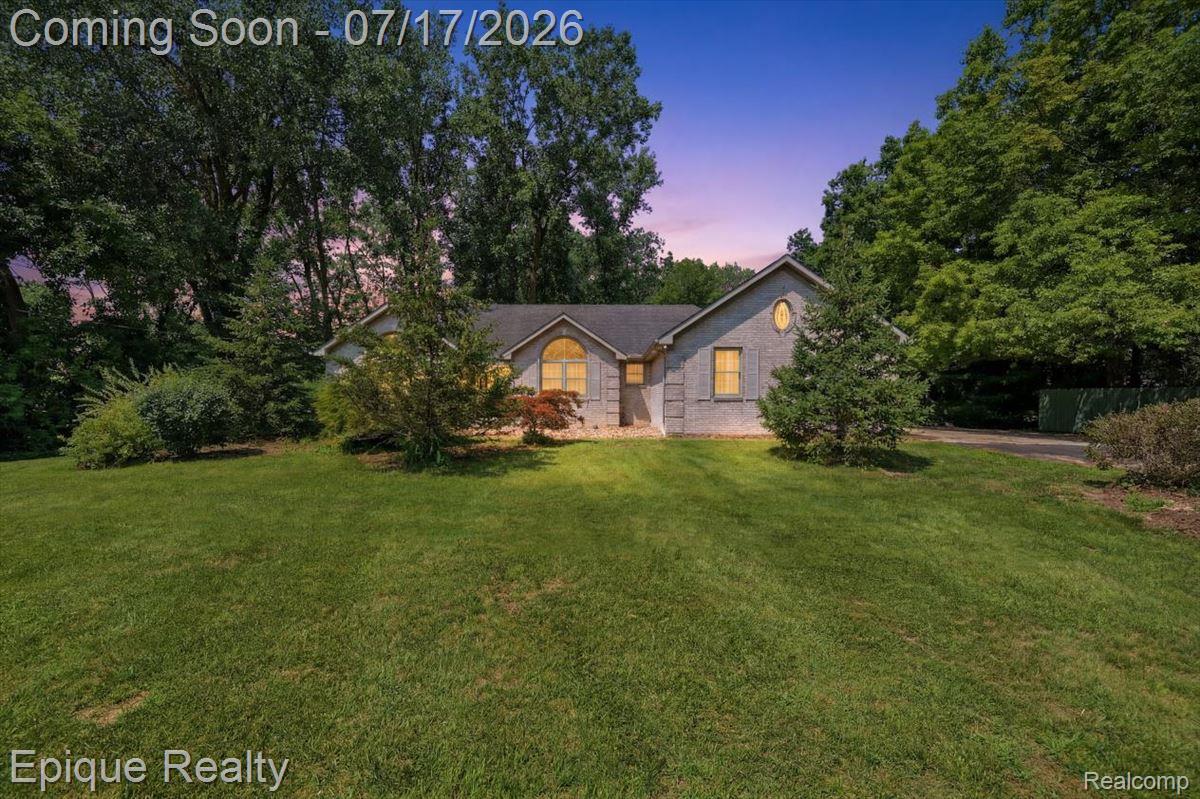 22520 Waltz Road New Boston, MI 48164 - Photo 1 of 43 Gray brick exterior featuring multiple arched windows, an oval window, mature trees, and a spacious front lawn