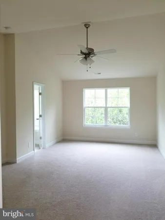 an empty room with windows and ceiling fan