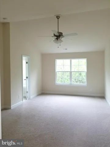 an empty room with windows and ceiling fan