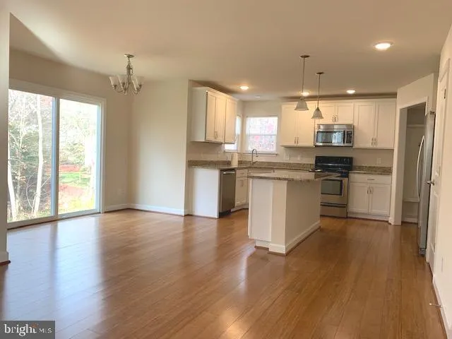 a kitchen with stainless steel appliances granite countertop wooden floors and white cabinets