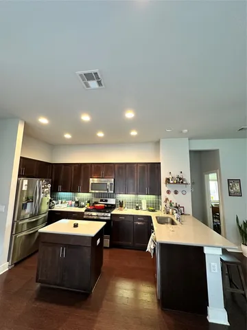 a kitchen with kitchen island a sink dishwasher stove and oven with wooden cabinets