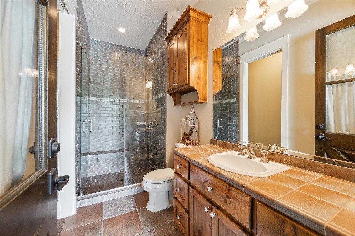 4511 Upper Oxbow Trace Fulshear, TX 77441 - Photo 32 of 40 a bathroom with a granite countertop sink a toilet a mirror and shower
