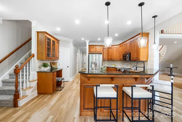 a kitchen with stainless steel appliances granite countertop a stove a sink a refrigerator a microwave oven with a dining table and chairs