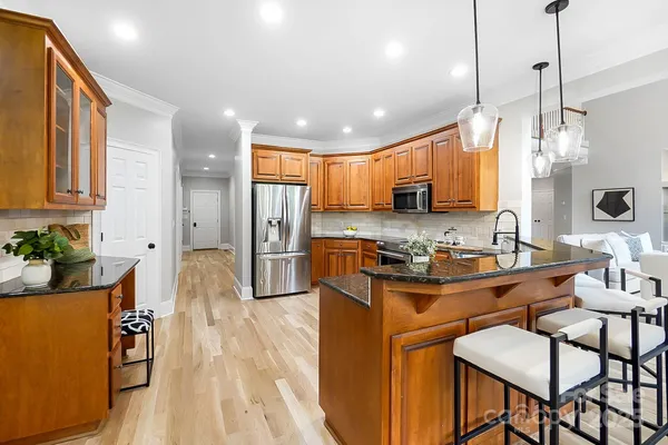 a kitchen with granite countertop a stove a sink a refrigerator and chairs