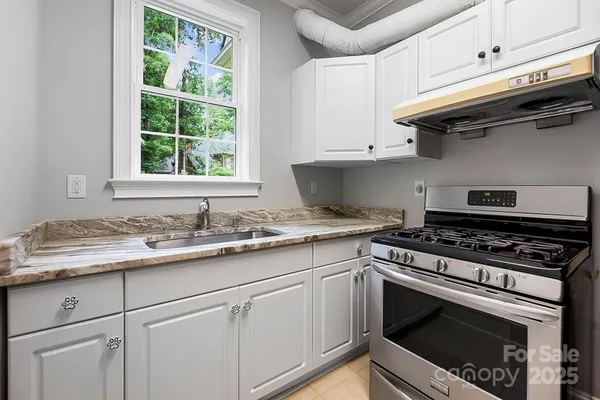 a kitchen with granite countertop a stove sink and cabinets