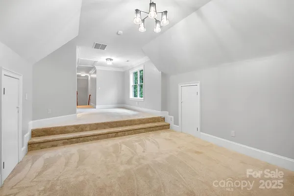 a spacious bedroom with a large bed and chandelier