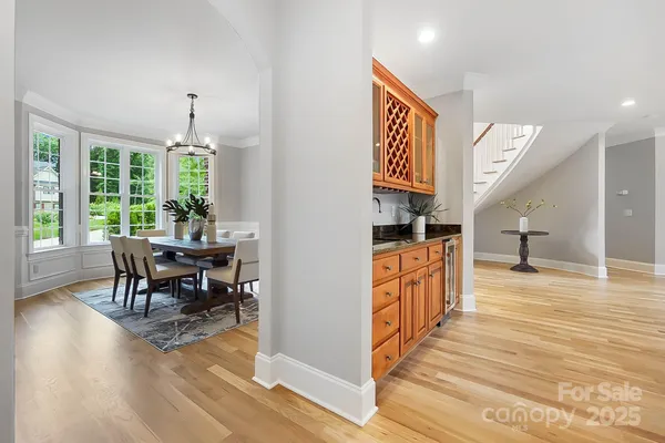 a open kitchen with granite countertop a stove a sink a dining table and chairs with wooden floor