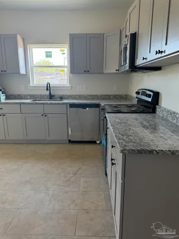 a kitchen with granite countertop a sink a stove and cabinets