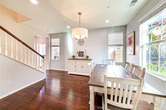 a dining room with wooden floor a chandelier a wooden table and chairs