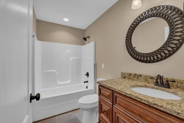 a bathroom with a granite countertop sink mirror vanity and toilet