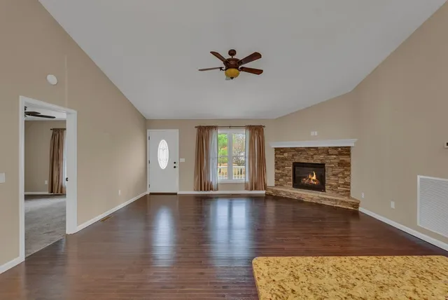 an empty room with wooden floor a fireplace and windows
