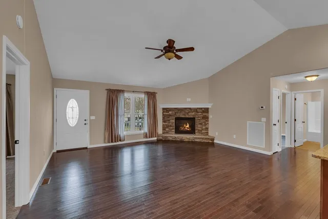 an empty room with wooden floor fireplace and windows