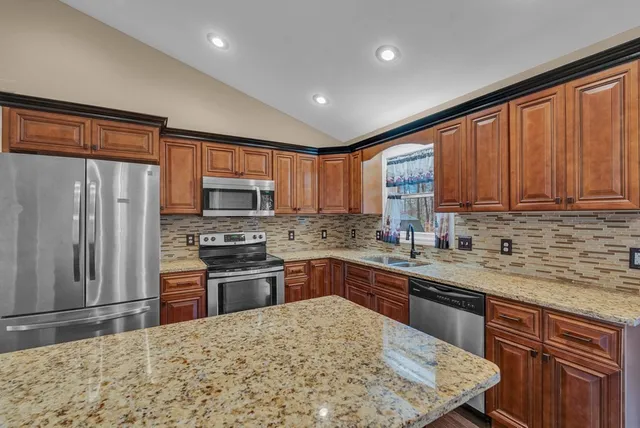 a kitchen with stainless steel appliances granite countertop a stove top oven a sink dishwasher a refrigerator and cabinets with wooden floor