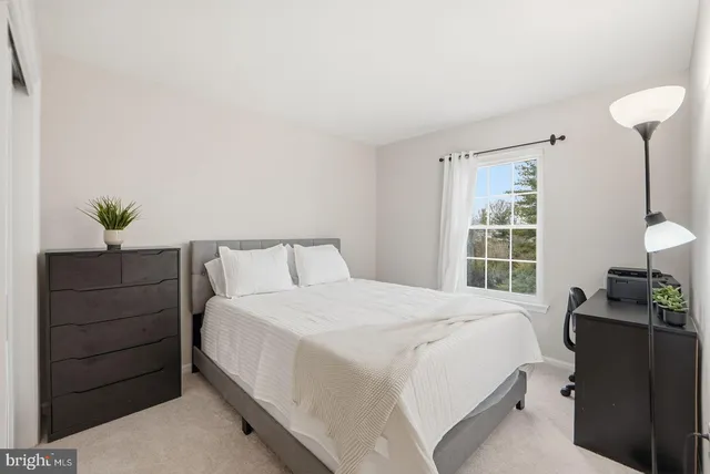 a bedroom with a bed and a lamp on dresser