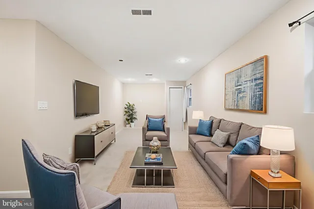 a living room with furniture a flat screen tv and kitchen view