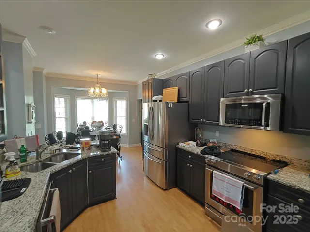 a kitchen with granite countertop a refrigerator stove and sink