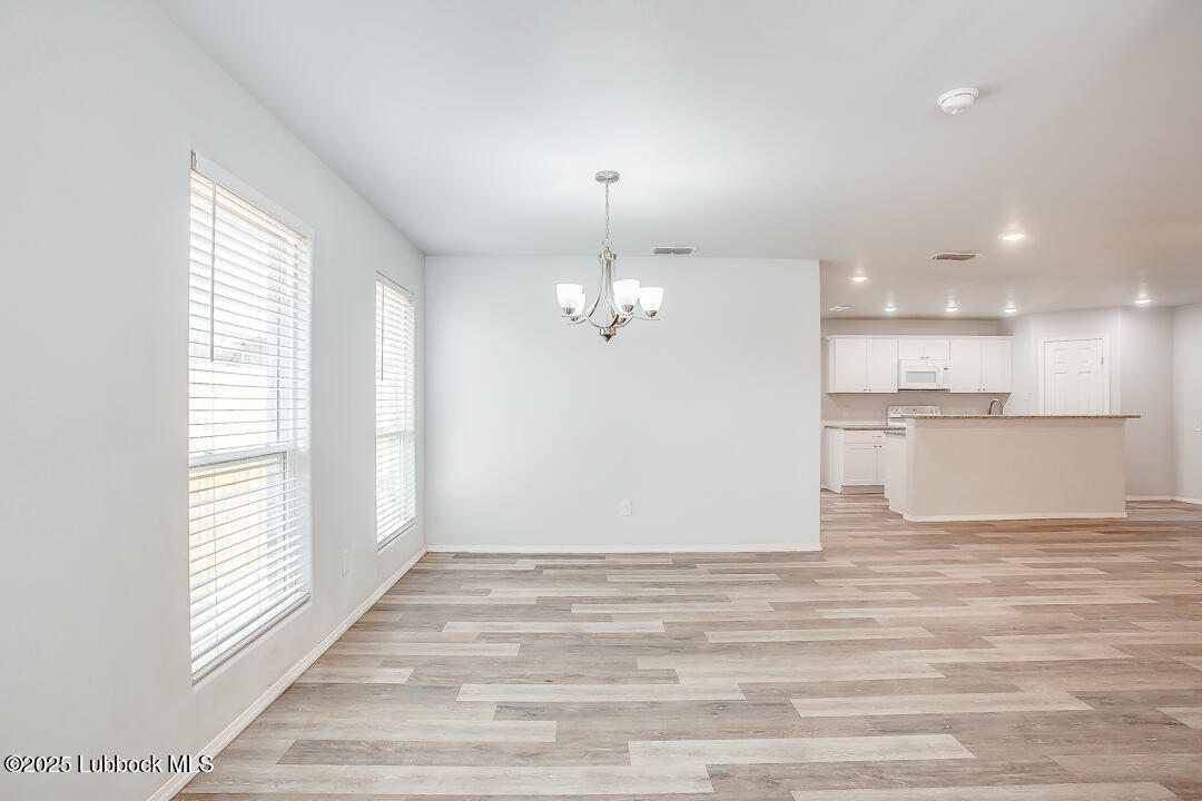 5514 Jarvis Street Lubbock, TX 79416 - Photo 2 of 16 an empty room with wooden floor kitchen view and windows