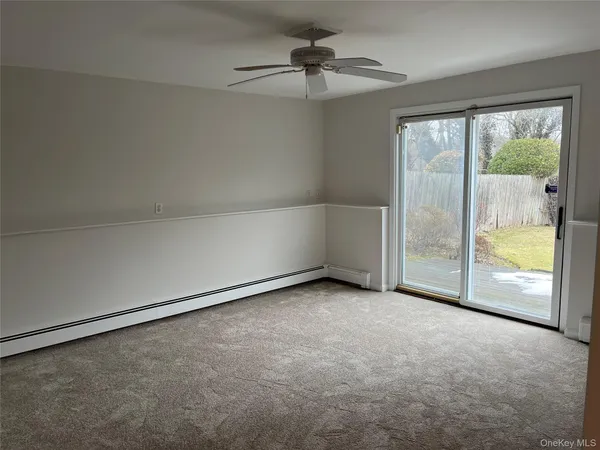 an empty room with a chandelier fan and windows