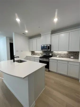 a kitchen with a sink a stove top oven and cabinets