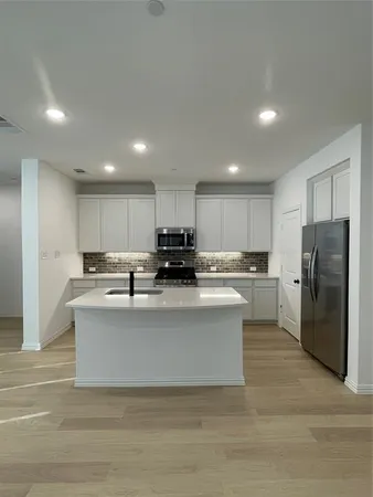 a view of kitchen with stainless steel appliances granite countertop lots of counter top and refrigerator