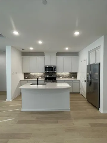 a view of kitchen with stainless steel appliances granite countertop lots of counter top and refrigerator