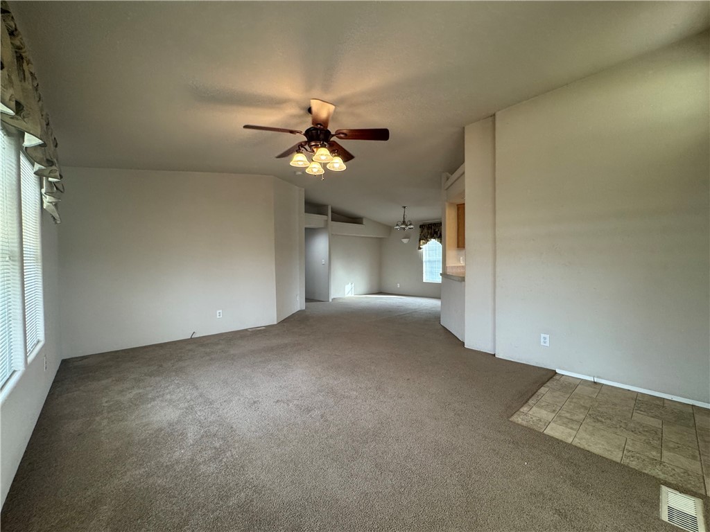 10044 Kent Road Mohave Valley, AZ 86440 - Photo 4 of 25 Empty room with light carpet, vaulted ceiling, and ceiling fan