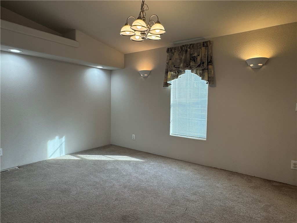 10044 Kent Road Mohave Valley, AZ 86440 - Photo 7 of 25 Spare room featuring a chandelier, carpet floors, and lofted ceiling