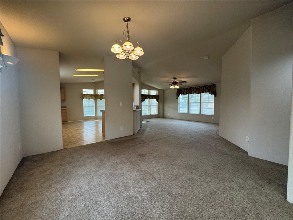 10044 Kent Road Mohave Valley, AZ 86440 - Photo 8 of 25 Empty room featuring a chandelier, light carpet, vaulted ceiling, and ceiling fan