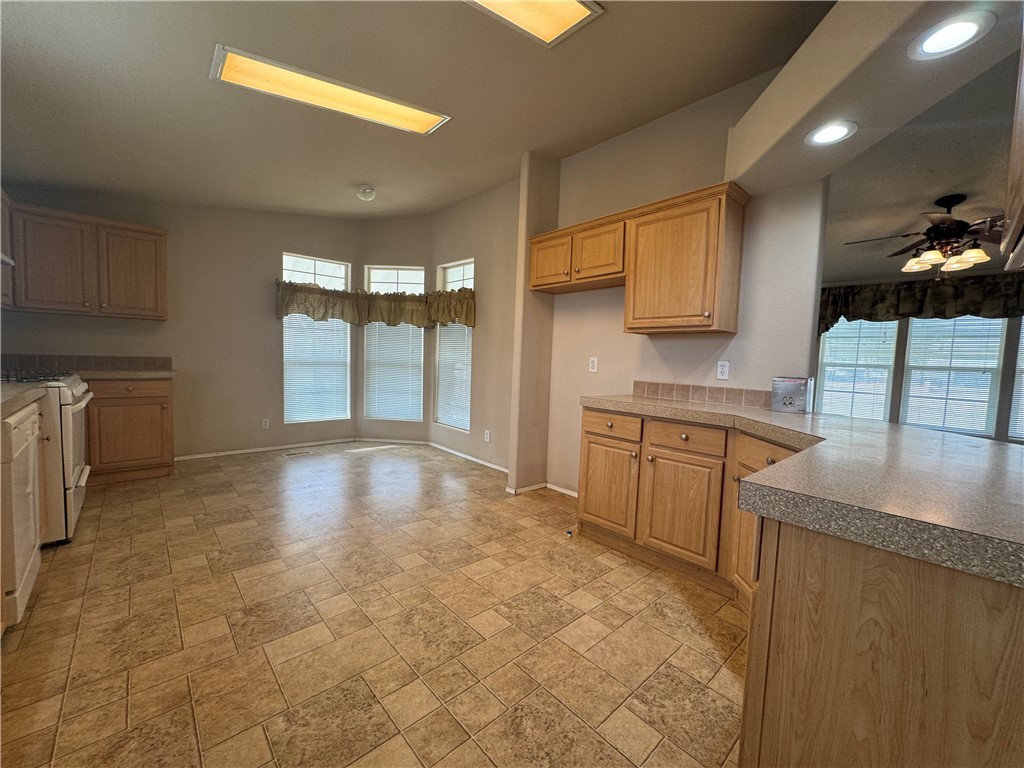 10044 Kent Road Mohave Valley, AZ 86440 - Photo 10 of 25 Kitchen with stone tile flooring, white appliances, a ceiling fan, recessed lighting, and a peninsula