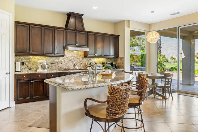 a kitchen with granite countertop a table chairs stove and cabinets