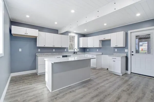 a large kitchen with kitchen island a sink white cabinets and stainless steel appliances