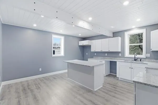 a large white kitchen with granite countertop a stove top oven a sink a dining table and chairs