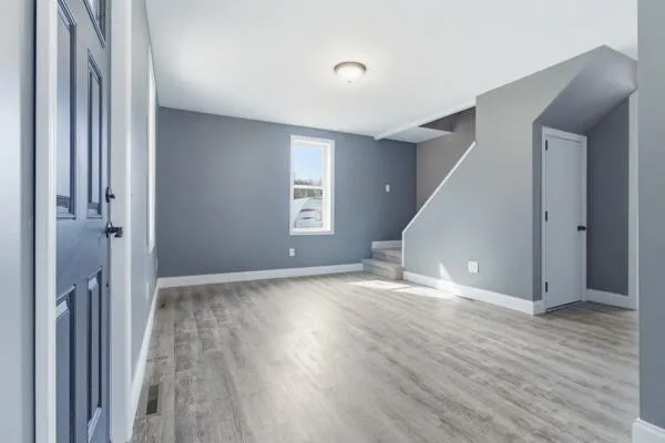 a view of an empty room with wooden floor and a window