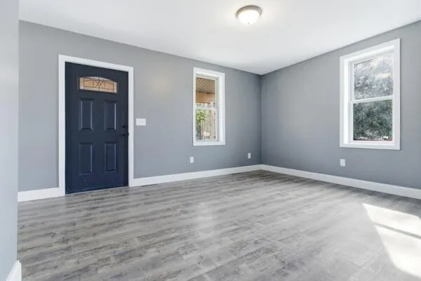 a view of an empty room with wooden floor and a window
