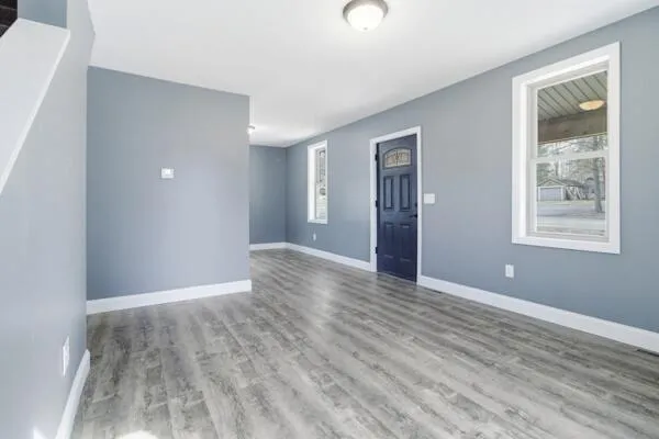 a view of an empty room with wooden floor and a window