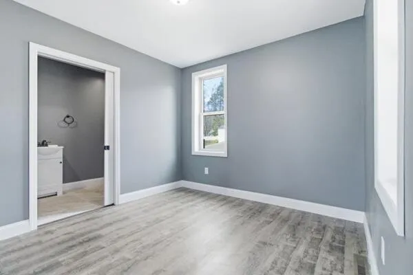 a view of an empty room with bathroom and a window