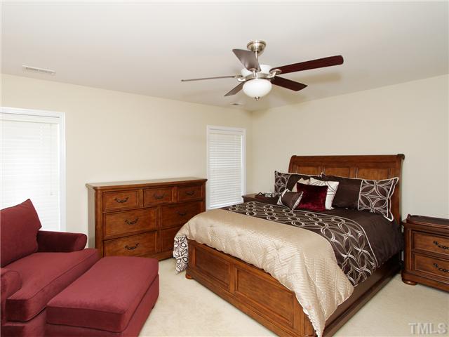 113 Poppy Hills Court Raleigh, NC 27603 - Photo 8 of 17 a bedroom with a bed and a chandelier