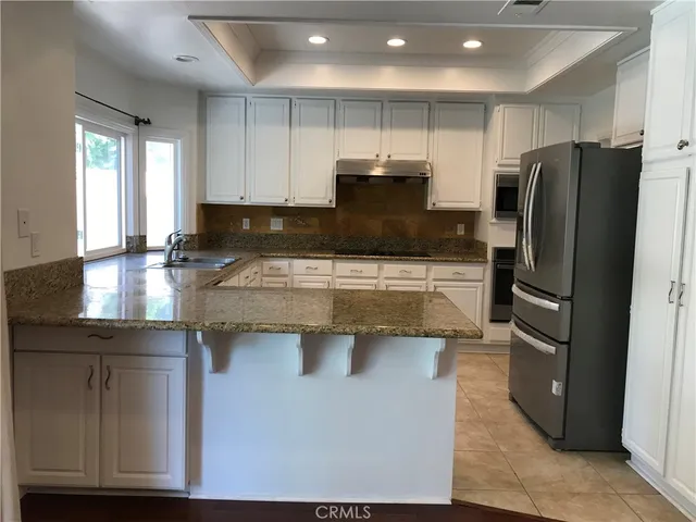 a kitchen with stainless steel appliances granite countertop a refrigerator a sink and a stove